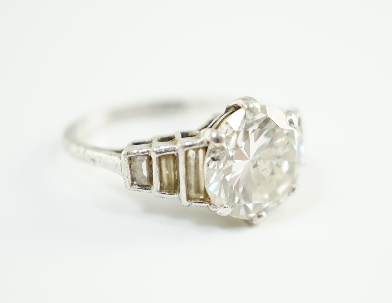 An Art Deco platinum and single stone diamond set ring, with six stone graduated baguette cut diamond set shoulders